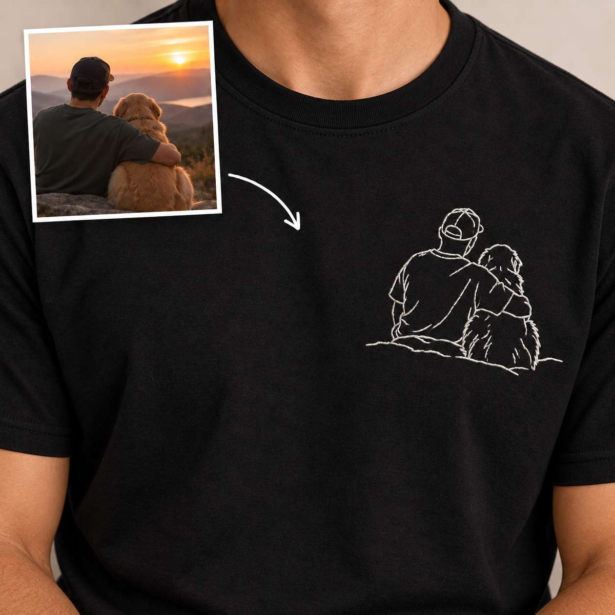 A close-up of a person wearing a black T-shirt with a small white line-art graphic on the chest showing two figures sitting together. An inset photo in the upper left shows a man hugging a dog at sunset, with an arrow pointing to the shirt graphic, suggesting a custom design based on a pet memorial or shared memory design.